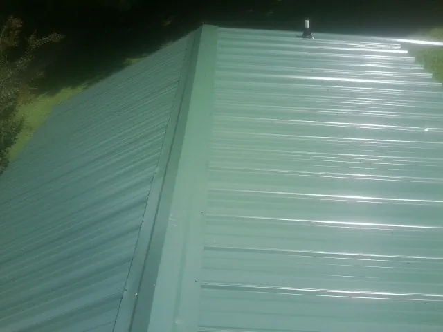 New green metal panels meeting at the ridge of a roof — Flat Roof Repair work by our crew in Flora