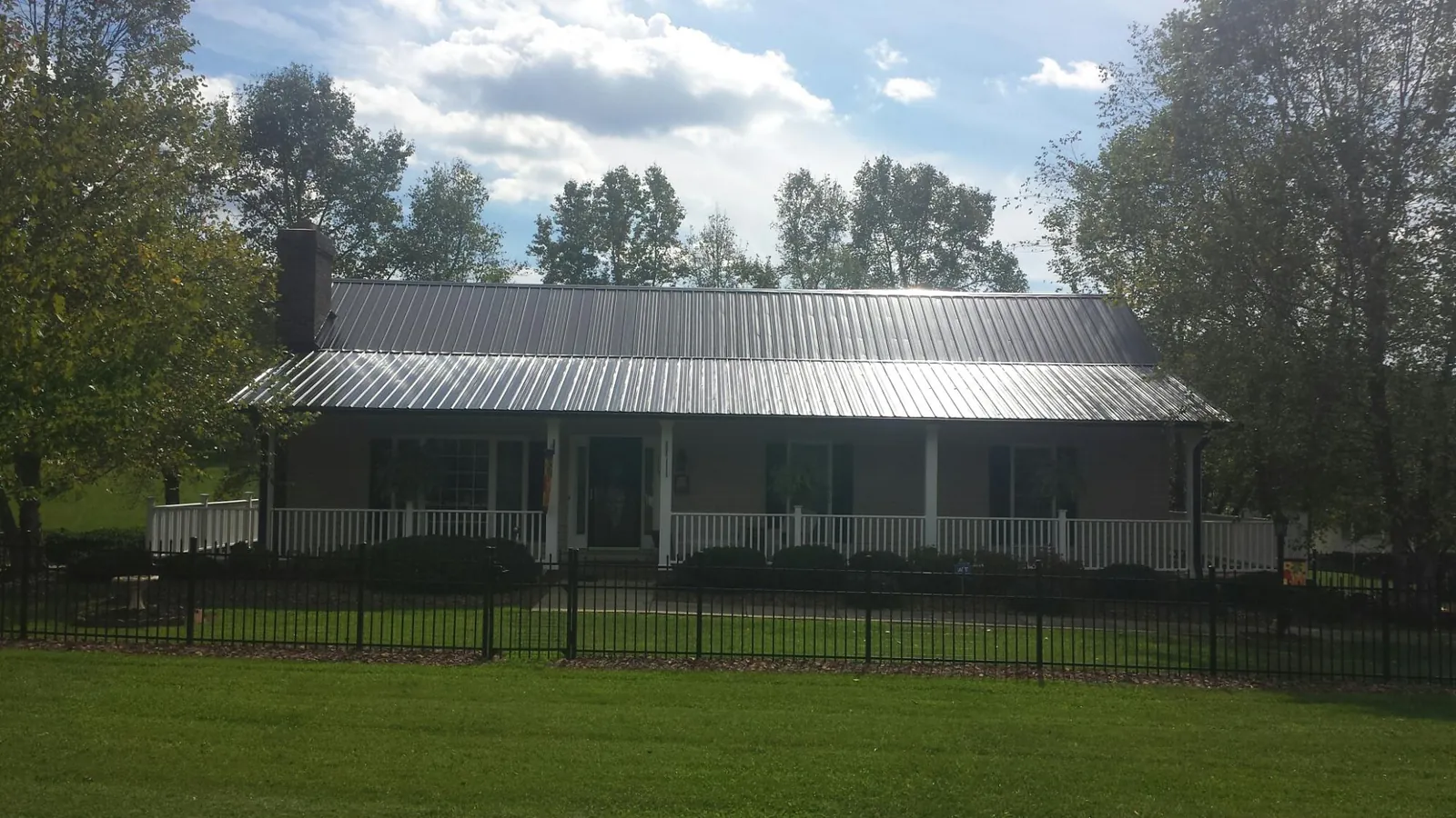 Gray metal roof on a brick ranch with a full width front porch — Gutter Guard Installation work by our crew in Flora